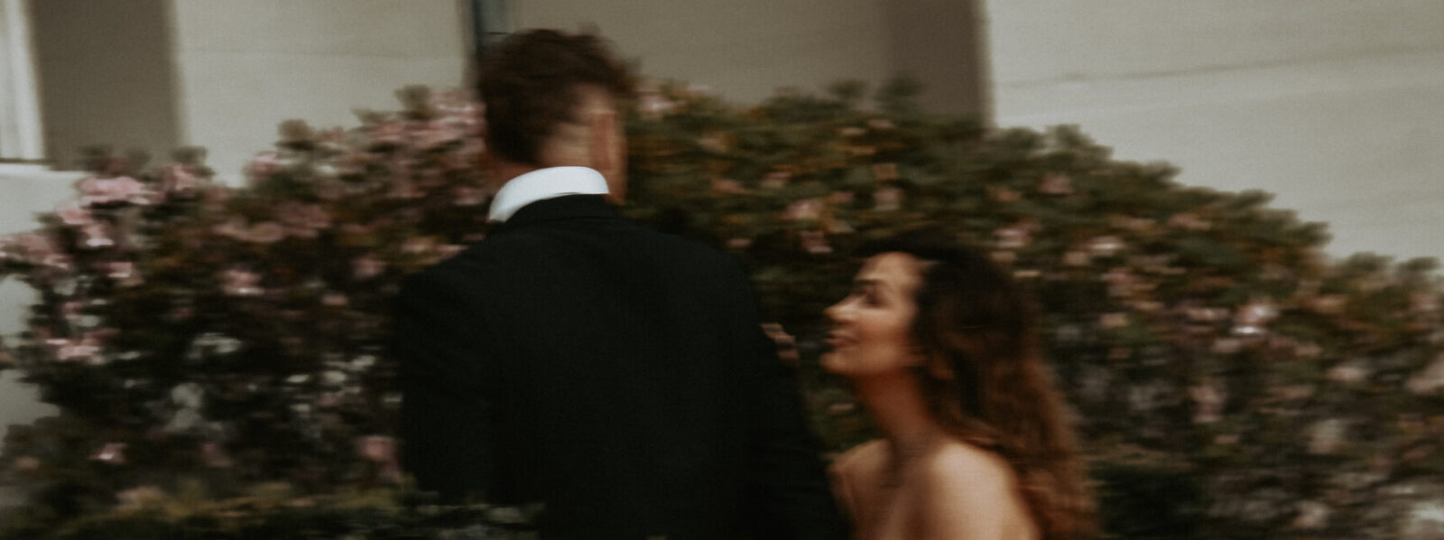 A cinematic motion blurred frame of a couple in evening wear turning toward each other in a garden